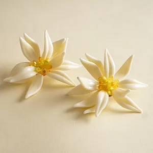 Detailansicht eleganter weißer Harzblumen-Ohrstecker mit gelben Kristallzentren.