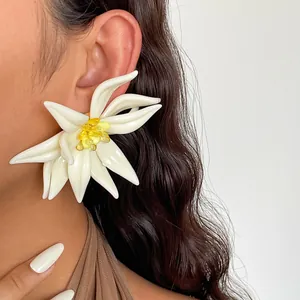 Detailaufnahme eines großen weißen Blumenohrrings aus Harz mit gelber Kristallmitte