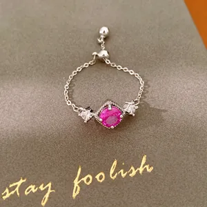 Detailweergave van een verstelbare zilveren kettingring met magenta zirkoon en stenen