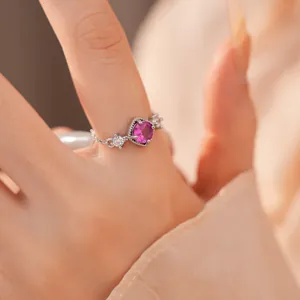 Close-up van een elegante zilveren ring met een roze steen en zirkonen om de vinger