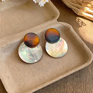 Vintage ronde schelp hangende oorbellen met glinsterende parelmoer en amber afwerking