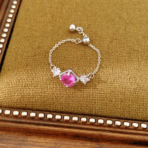 Detailopname van een zilveren kettingring met roze edelsteen en schuifsluiting.