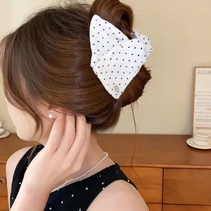 Detailopname van een witte stoffen haarklem met stippen, gestyled in een knot