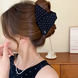 Detailopname van een stijlvolle zwarte gestipte stoffen haarklem in een elegant haarknotje