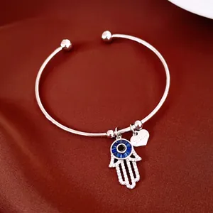 Gros plan des breloques main de Fatma et cœur sur un bracelet jonc argenté avec zircons