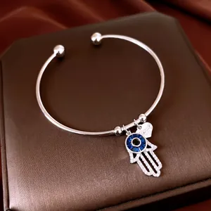 Vue macro détaillée d'une main de Hamsa en argent et d'un pendentif œil bleu sur un bracelet.