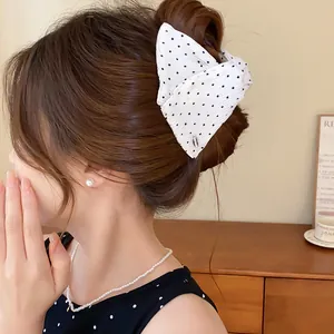 Detailweergave van een witte haarklem met zwarte stippen en stoffen strik op een knot