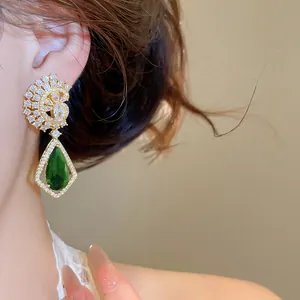 Dettaglio di orecchini vintage con goccia verde smeraldo e pavé di cristalli lucenti