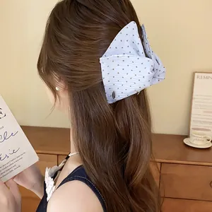 Detailopname van een blauwe haarklem met stippenprint in lang golvend haar