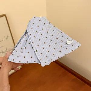 Detailweergave van een lichtblauwe haarklem van stof met stippen en zilveren tag