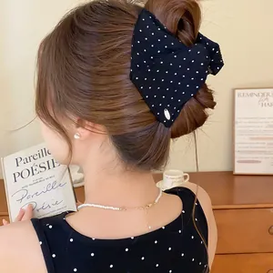 Detailopname van een zwarte haarklem met witte stippen gestyled in een vrouwen haarknot
