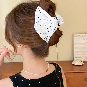 Detailopname van de witte haarclip met stippen en strik op een stijlvol opgestoken kapsel