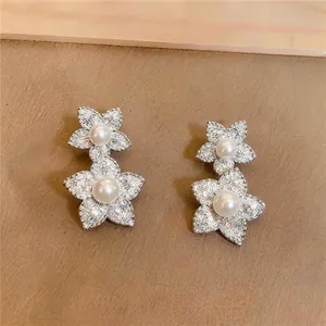 Detailansicht der silberfarbenen Blumenohrringe mit Zirkonia und weißen Perlen.