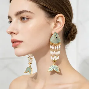 Exotic enamel fish and pearl tassel drop earrings in gold plated finish on model.