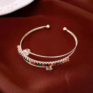Vue détaillée d'un élégant bracelet jonc doré multicouche orné de zircons colorés.