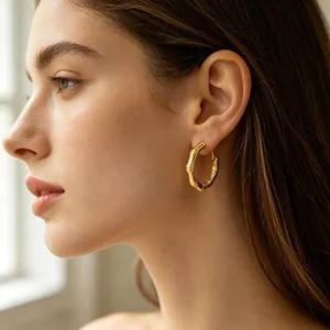 Élégantes créoles en acier inoxydable doré au design bambou pour femme portées par modèle