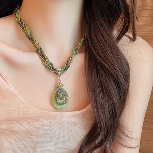 Gros plan détaillé d'un collier de perles bohème avec un pendentif goutte en cristal.