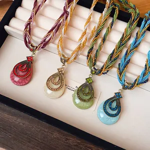 Vue détaillée de colliers de perles de cristal bohèmes avec pendentifs en strass en quatre couleurs.