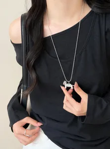 Detailed shot of a silver ball chain necklace with a cute dog pendant and bow detail.