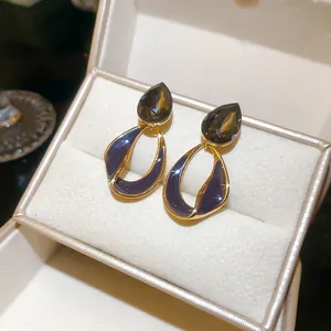 Detail of Maillard style earrings with 18k gold plating and dark smoky teardrop stone.