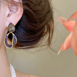 Close-up of retro 18k gold plated earrings with grey crystal and purple enamel drop