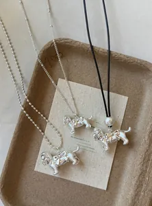 Close-up of silver metal dog pendant necklaces with bow details on a rustic tray