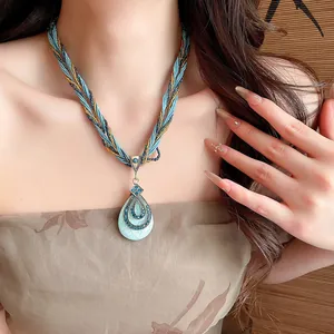 Détail d'un collier pendentif goutte bohème avec perles de cristal bleu et design orné complexe