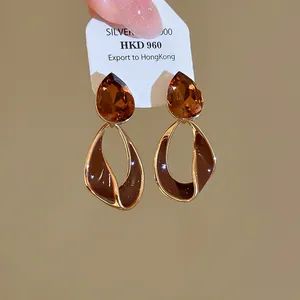 Close-up of vintage 18k gold plated earrings with amber gemstone and brown enamel