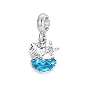 Detailaufnahme eines silbernen Meeresanhängers mit Seestern, Muschel und blauen Wellen.