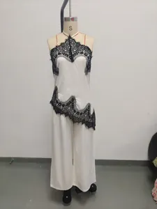 Set canotta e pantaloni in raso bianco con pizzo nero mostrato su un manichino da sarta