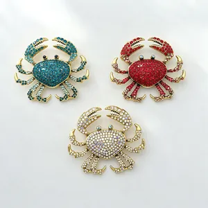 Detailed view of rhinestone crab brooches in teal, red, and white on gold base.