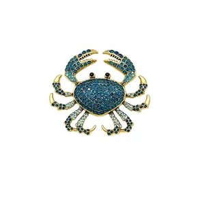 Elegant gold-toned crab brooch encrusted with sparkling blue and aqua rhinestones on white background