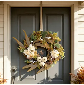 Corona de cosecha de otoño con calabazas blancas y hojas de arce en la puerta