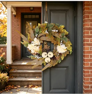 Corona de otoño con calabazas blancas y hojas de arce en una puerta oscura, detalle