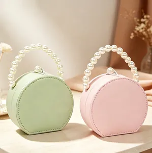 Elegante portagioie rotondo portatile con manico in perle in verde menta e rosa pastello.