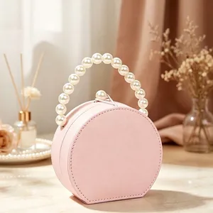 Elegante portagioie rosa rotondo a forma di borsa con manico in perle e chiusura a scatto.