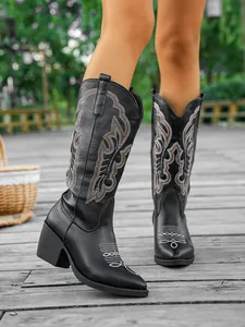 Élégantes bottes de cowboy western noires avec broderies sur terrasse en bois.