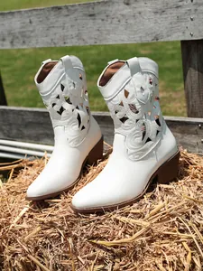 Close-up of white pointed-toe western boots with intricate hollow-out embroidery
