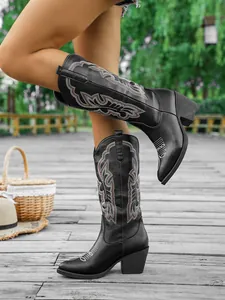 Vue détaillée de bottes de cowboy brodées rétro noires avec bout pointu et talon épais.