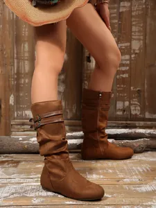 Close-up of brown suede slouchy boots with double buckle straps and a side zipper