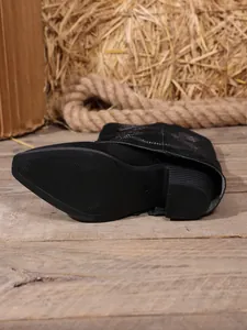 Detailed view of black embroidered knight boots with a pointed toe and thick heel