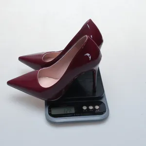 Burgundy patent leather pointed toe stiletto pump on a scale showing 126g weight