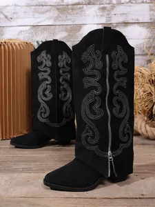 Detail view of black suede knight boots featuring intricate embroidery and front zipper.