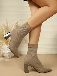 Close-up of tan knitted sock boots with shimmering finish and chunky high heels.