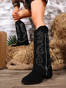 Detailed view of black suede high-top boots with ornate embroidery and side zipper