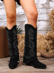 Detail of black embroidered knee-high western boots with pointed toe and folded cuff.