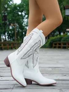 Detaillierte Seitenansicht weißer Western-Cowboystiefel mit brauner Stickerei im Freien.