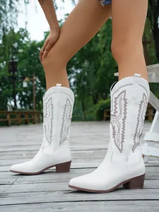Detailansicht weißer bestickter Western-Cowboystiefel auf einer Holzterrasse im Freien