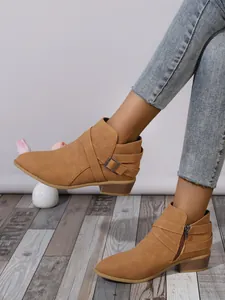 Detailed view of tan pointed toe ankle boots with block heel and side buckle straps