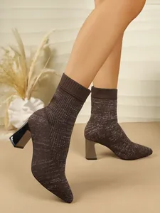 Close-up of brown knitted sock boots with sparkling glitter detail and chunky high heels